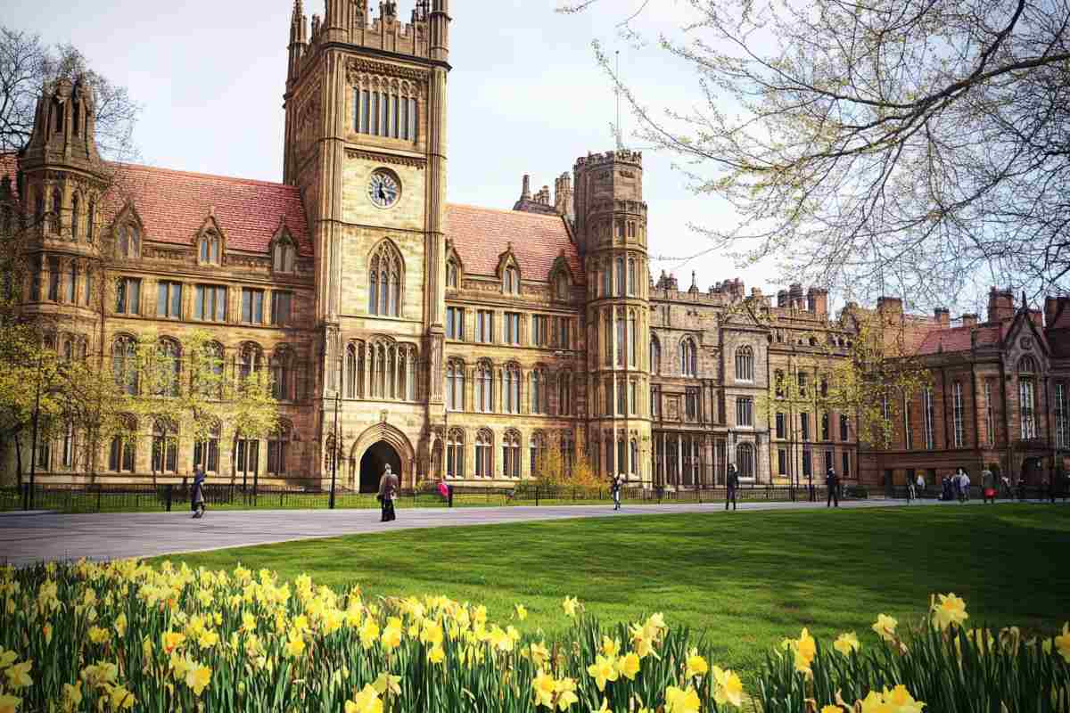 Beautiful view of the University of Manchester with historic architecture, blooming flowers, and students walking on campus.